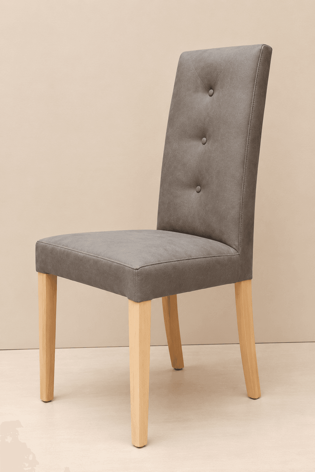 Finished dining chair upholstered in grey with three-button detailing on natural beech legs, studio shot